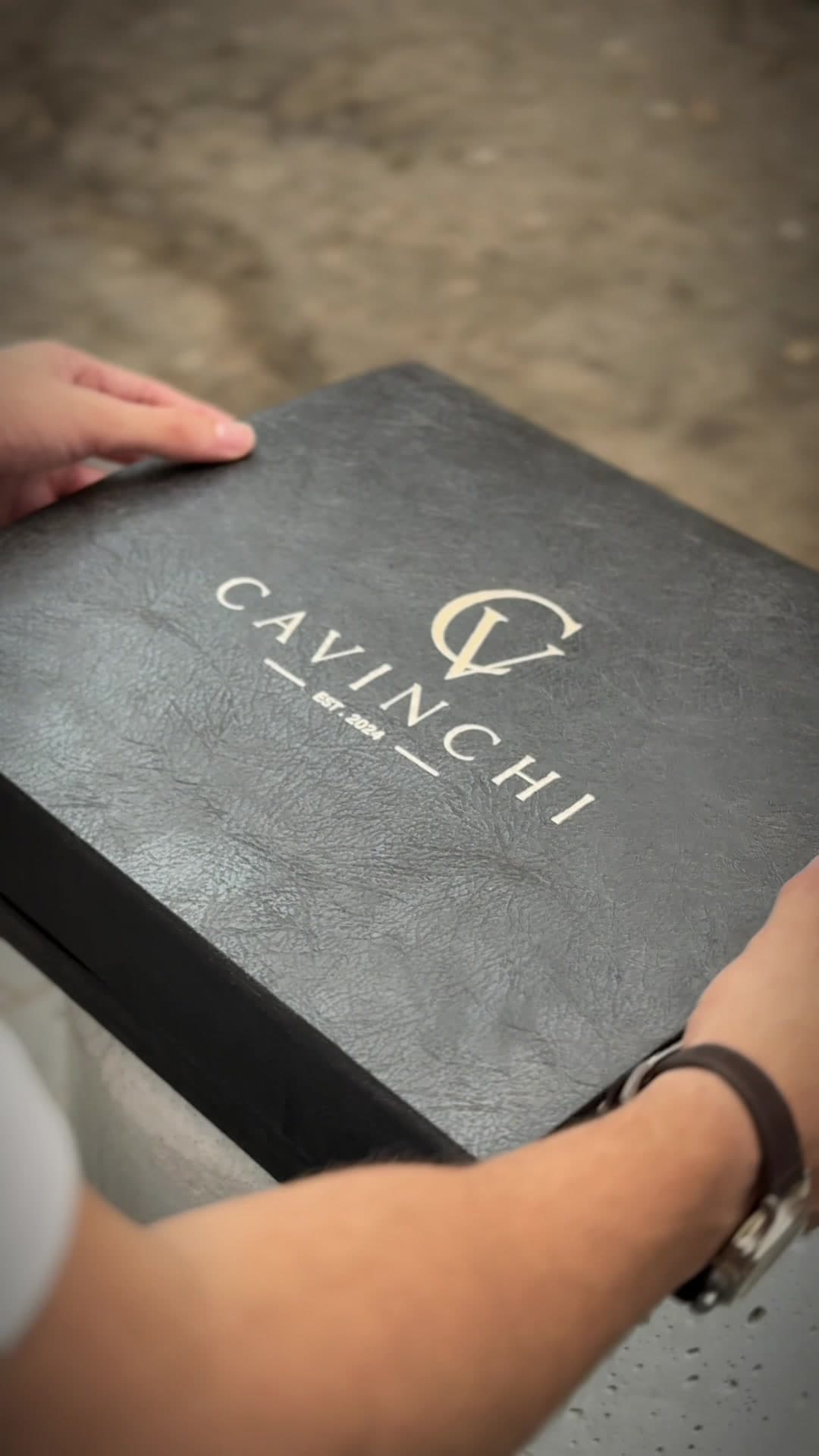 The closed box held in two hands, the mark foiled on the textured lid